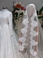 Luxury modest hijab wedding dress ball gown with long sleeves, high neck corset bodice, lace appliqué and included lace veil, photographed in a bridal atelier.