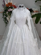 Luxury modest hijab wedding dress ball gown with long sleeves, high neck corset bodice, lace appliqué and included lace veil, photographed in a bridal atelier.