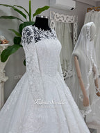 Luxury white hijab wedding dress with long floral lace sleeves, a beaded princess skirt, illusion boat neckline, and a matching premium lace-edged veil.