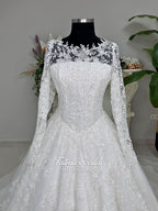 Luxury white hijab wedding dress with long floral lace sleeves, a beaded princess skirt, illusion boat neckline, and a matching premium lace-edged veil.