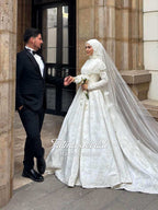 Elegant white lace Muslim wedding gown with flowing veil by Fatma Sevildi