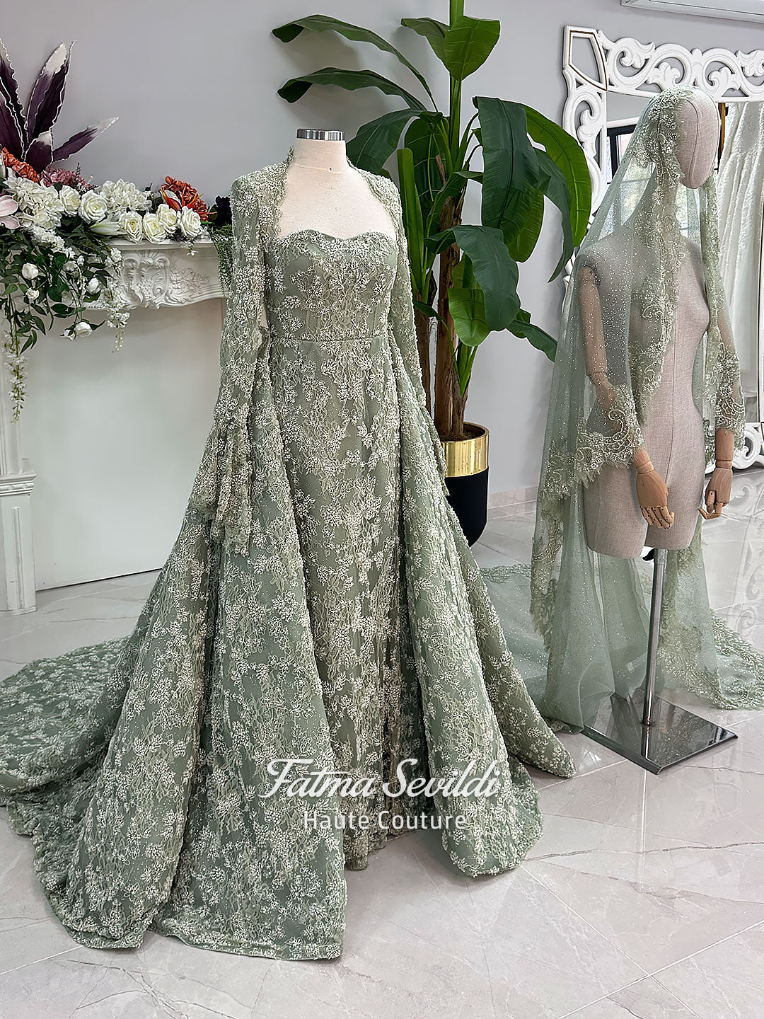 Sage green evening dress with beaded floral lace, a sweetheart neckline and long sleeves with flared lace cuffs, displayed on a mannequin.