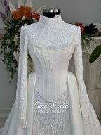 Luxury hijab wedding dress with long sleeves, high neck, beaded lace mermaid silhouette and detachable overskirt, veiled bridal set. Handmade couture modest bridal gown with lace-up corset back and sparkling embroidery.