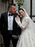 Fatma Sevildi Couture lace wedding dress on a mannequin, featuring a high neckline, long sleeves and intricate floral embellishment.