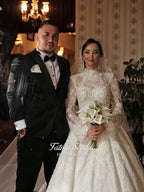 Fatma Sevildi Couture lace wedding dress on a mannequin, featuring a high neckline, long sleeves and intricate floral embellishment.