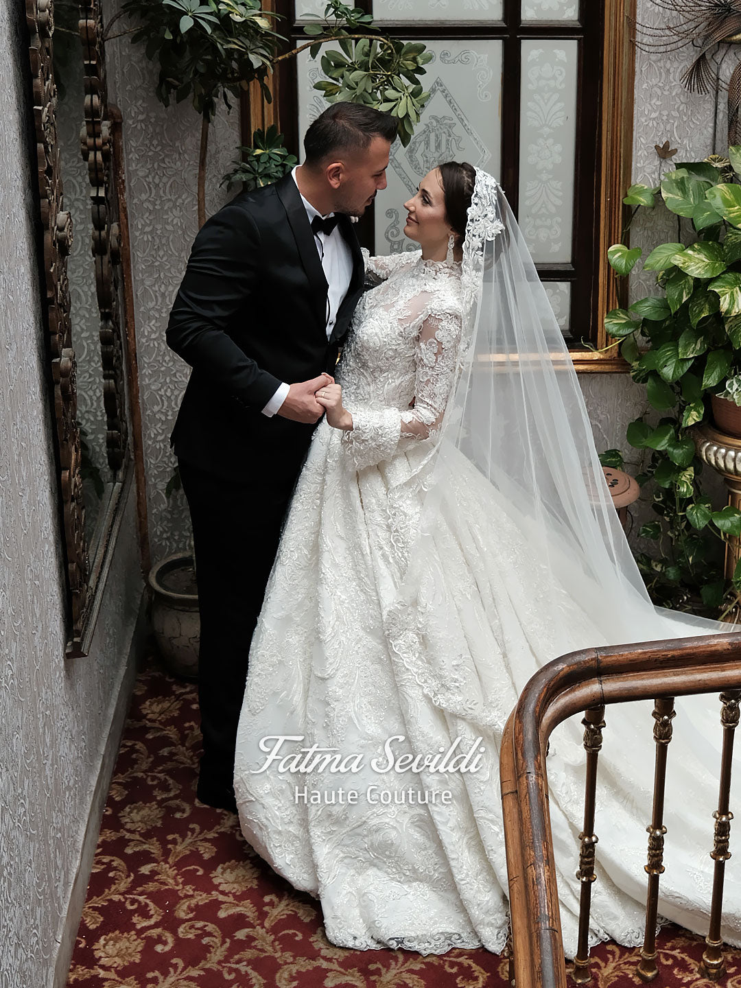Fatma Sevildi Couture lace wedding dress on a mannequin, featuring a high neckline, long sleeves and intricate floral embellishment.