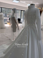 White A-line satin hijab wedding dress with long sleeves, high neckline, floral appliqué embroidery and an included premium lace mantilla veil for a modest Muslim bridal look.