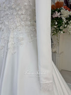 White A-line satin hijab wedding dress with long sleeves, high neckline, floral appliqué embroidery and an included premium lace mantilla veil for a modest Muslim bridal look.