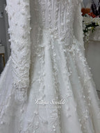 White hijab wedding dress with long sleeves, high lace neckline, floral embroidery and a full modest bridal skirt, shown with a premium lace veil. Luxury Muslim wedding gown with detailed lace and elegant full coverage.