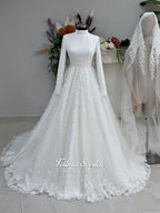 White A-line hijab wedding dress with a high-neck satin bodice, long sleeves, and a beaded botanical lace tulle skirt with a sweeping train. Displayed beside a coordinating lace-trimmed veil.