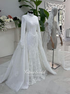White hijab wedding dress with long sleeves, floral lace, high neckline and detachable overskirt, styled with a premium lace veil. Luxury modest bridal gown designed for a fully covered Muslim bridal look.