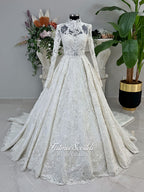 Ivory luxury hijab wedding dress featuring long lace sleeves, a high neckline, full beaded floral lace princess skirt, dramatic train and coordinating premium lace veil.