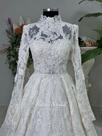 Ivory luxury hijab wedding dress featuring long lace sleeves, a high neckline, full beaded floral lace princess skirt, dramatic train and coordinating premium lace veil.