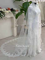 Luxury hijab wedding dress with mermaid silhouette and basque corset, featuring long sleeves, high neck lace, and a premium lace veil. Photographed on a mannequin in a bridal atelier setting.