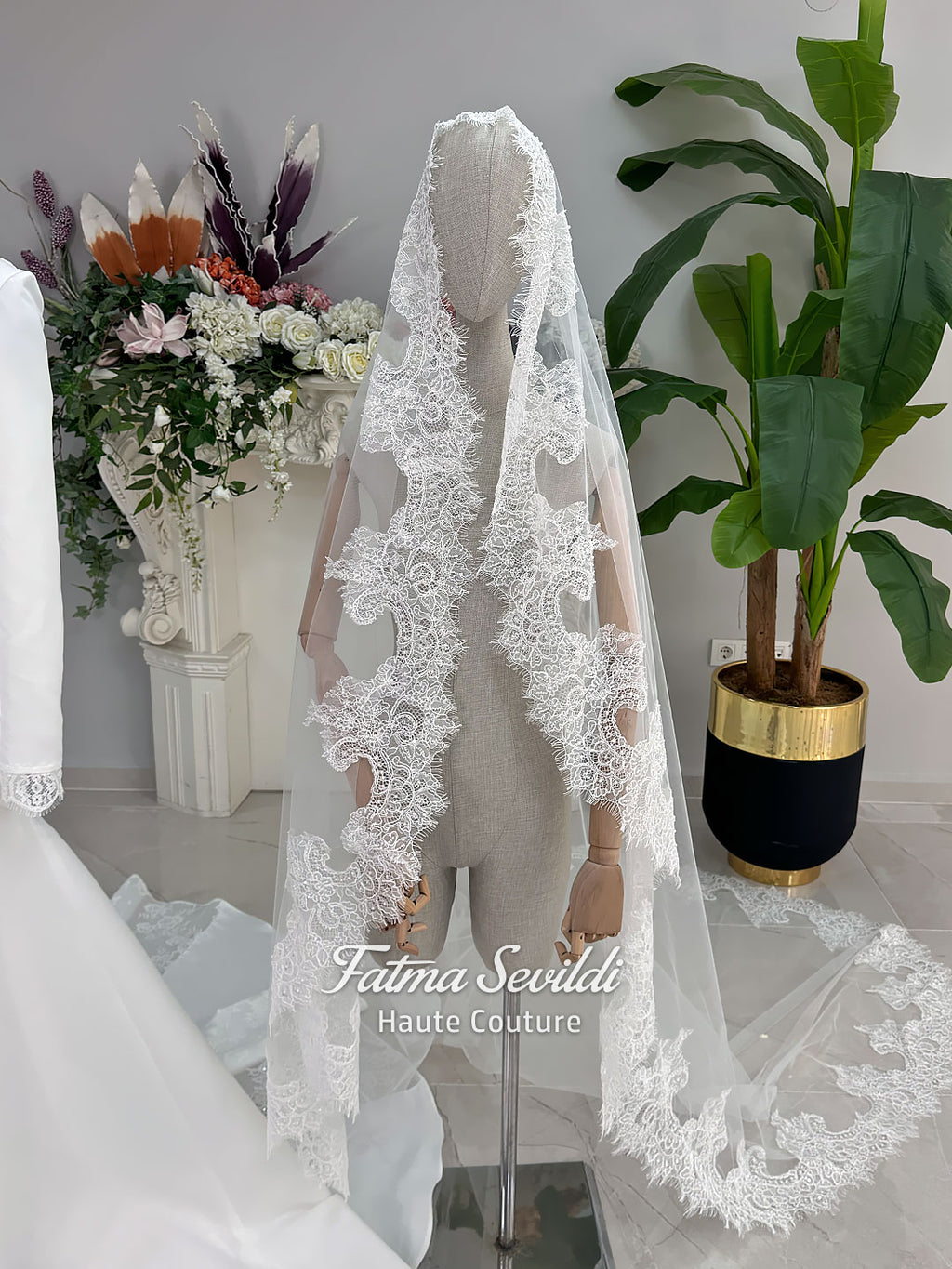 White mermaid satin-look hijab wedding dress with a high neckline, long sleeves, fitted bodice and floor-length train, styled with an intricate floral lace bridal veil. Fatma Sevildi Haute Couture modest bridal design.