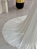 Ivory long sleeve hijab wedding dress with detachable lace-edged cape, floral beaded embroidery, high neckline and floor-length A-line modest bridal silhouette. Designed for Muslim brides seeking an elegant luxury wedding gown with full coverage.