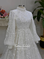 Luxury Muslim wedding dress with high neck, long sleeves, beaded lace embroidery, full A-line skirt, and matching premium lace veil. Elegant modest bridal gown custom made for hijab brides seeking a couture wedding look.