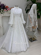 Luxury Muslim wedding dress with high neck, long sleeves, beaded lace embroidery, full A-line skirt, and matching premium lace veil. Elegant modest bridal gown custom made for hijab brides seeking a couture wedding look.