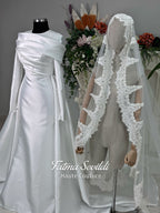 Luxury satin hijab wedding dress with off-shoulder long sleeves and an A-line silhouette, shown with premium lace veil and dramatic train. Custom couture modest bridal gown design with elegant draping and pearl details.