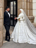 Elegant white lace Muslim wedding gown with flowing veil by Fatma Sevildi