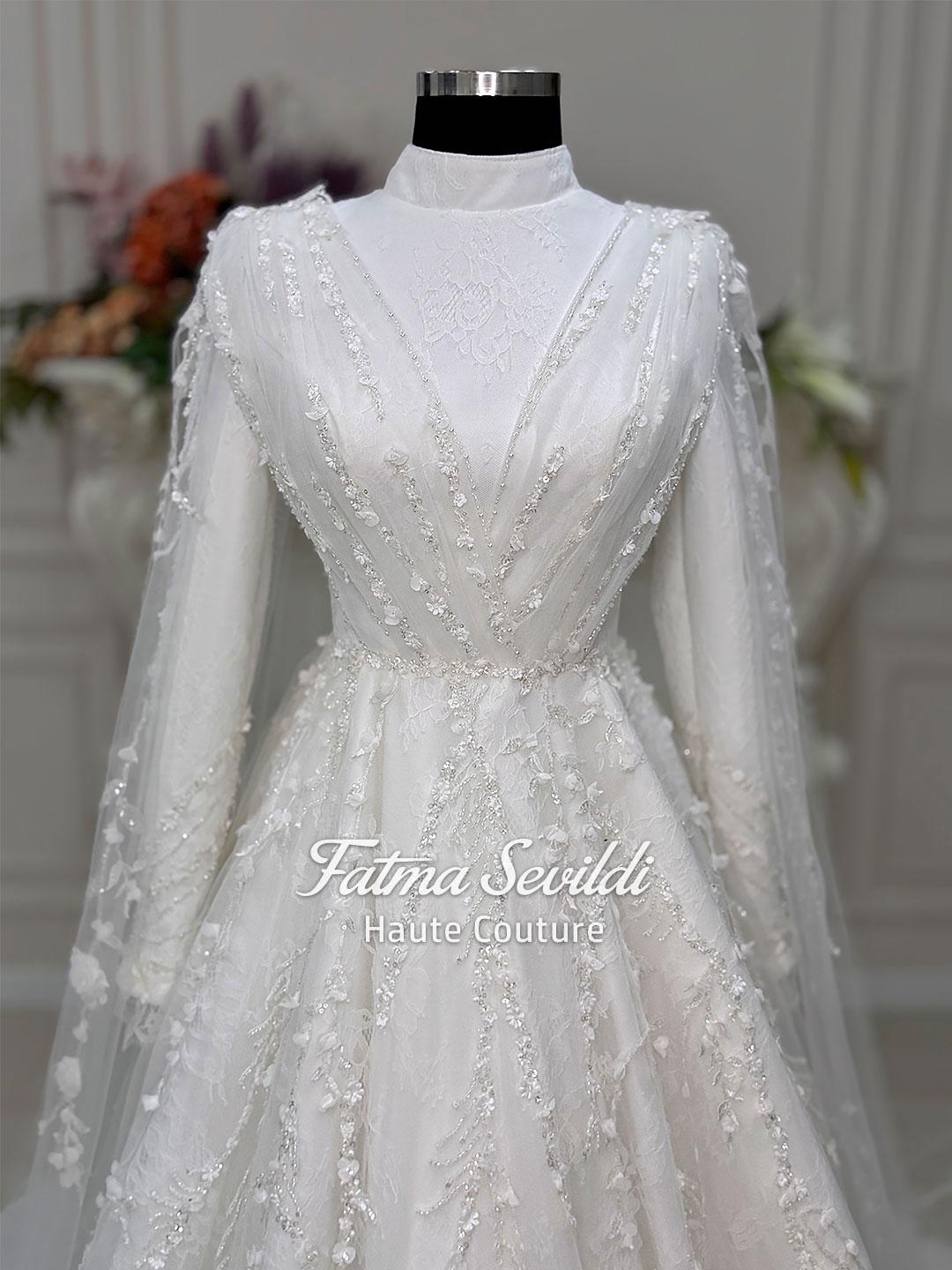 White long-sleeved modest bridal gown with floral lace, silver beading and veil