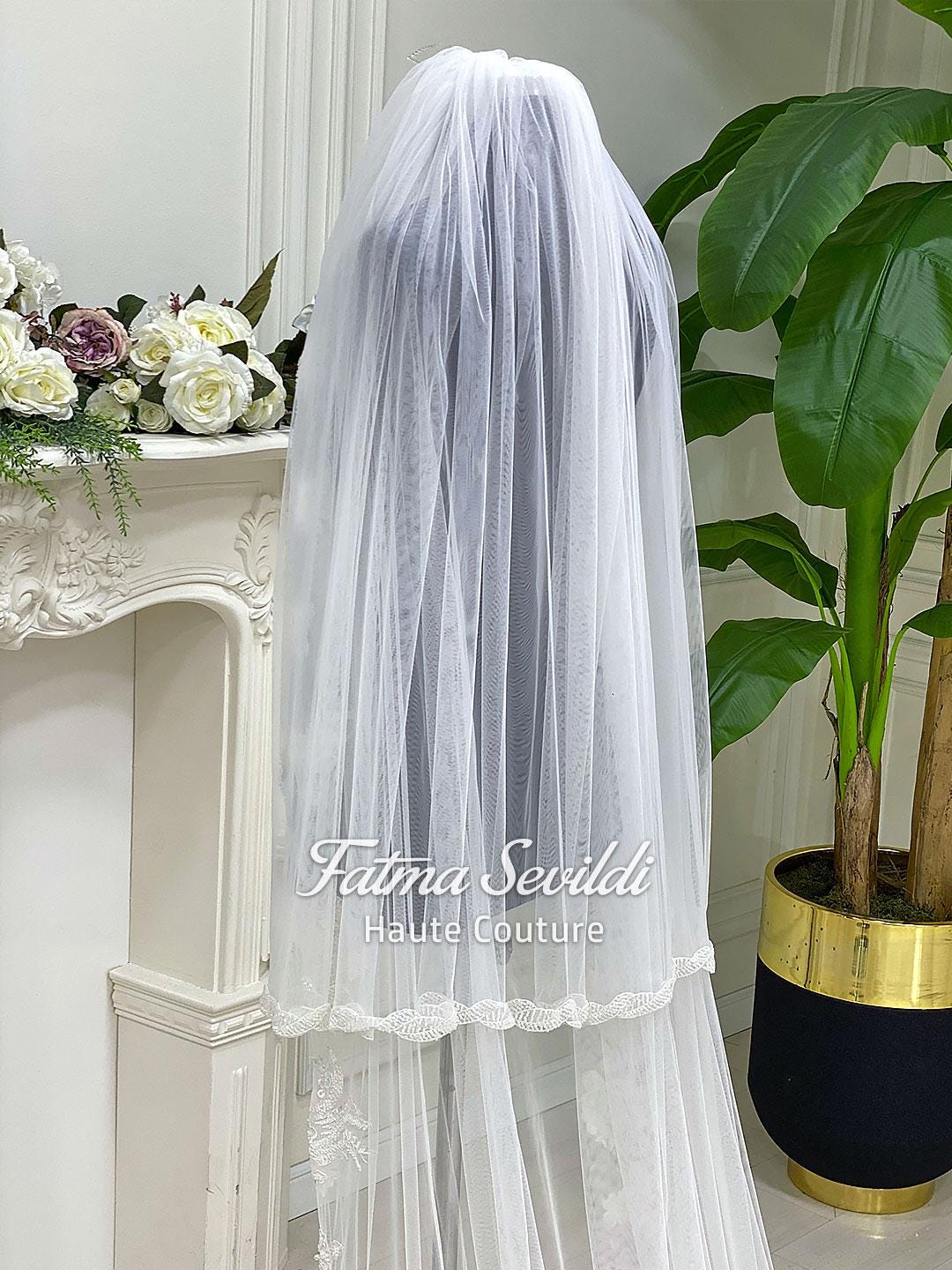 Delicate white tulle veil with lace trim on mannequin for veiled hijab wedding dress