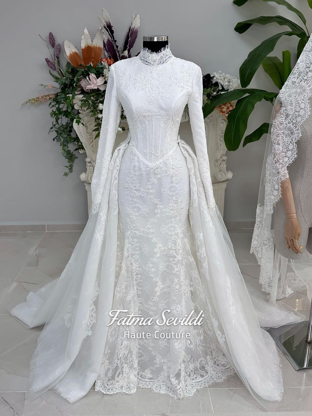 White hijab wedding dress with long sleeves, floral lace, high neckline and detachable overskirt, styled with a premium lace veil. Luxury modest bridal gown designed for a fully covered Muslim bridal look.