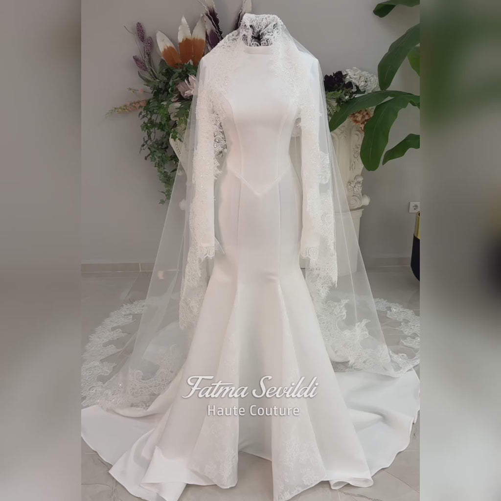 White mermaid satin-look hijab wedding dress with a high neckline, long sleeves, fitted bodice and floor-length train, styled with an intricate floral lace bridal veil. Fatma Sevildi Haute Couture modest bridal design.
