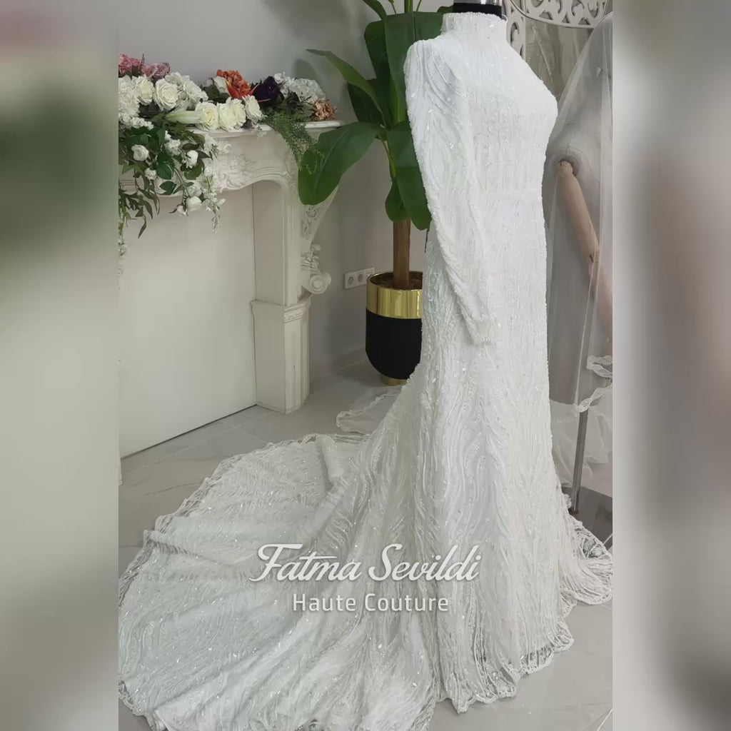 Luxury hijab wedding dress with long sleeves, high neck, beaded lace mermaid silhouette and detachable overskirt, veiled bridal set. Handmade couture modest bridal gown with lace-up corset back and sparkling embroidery.