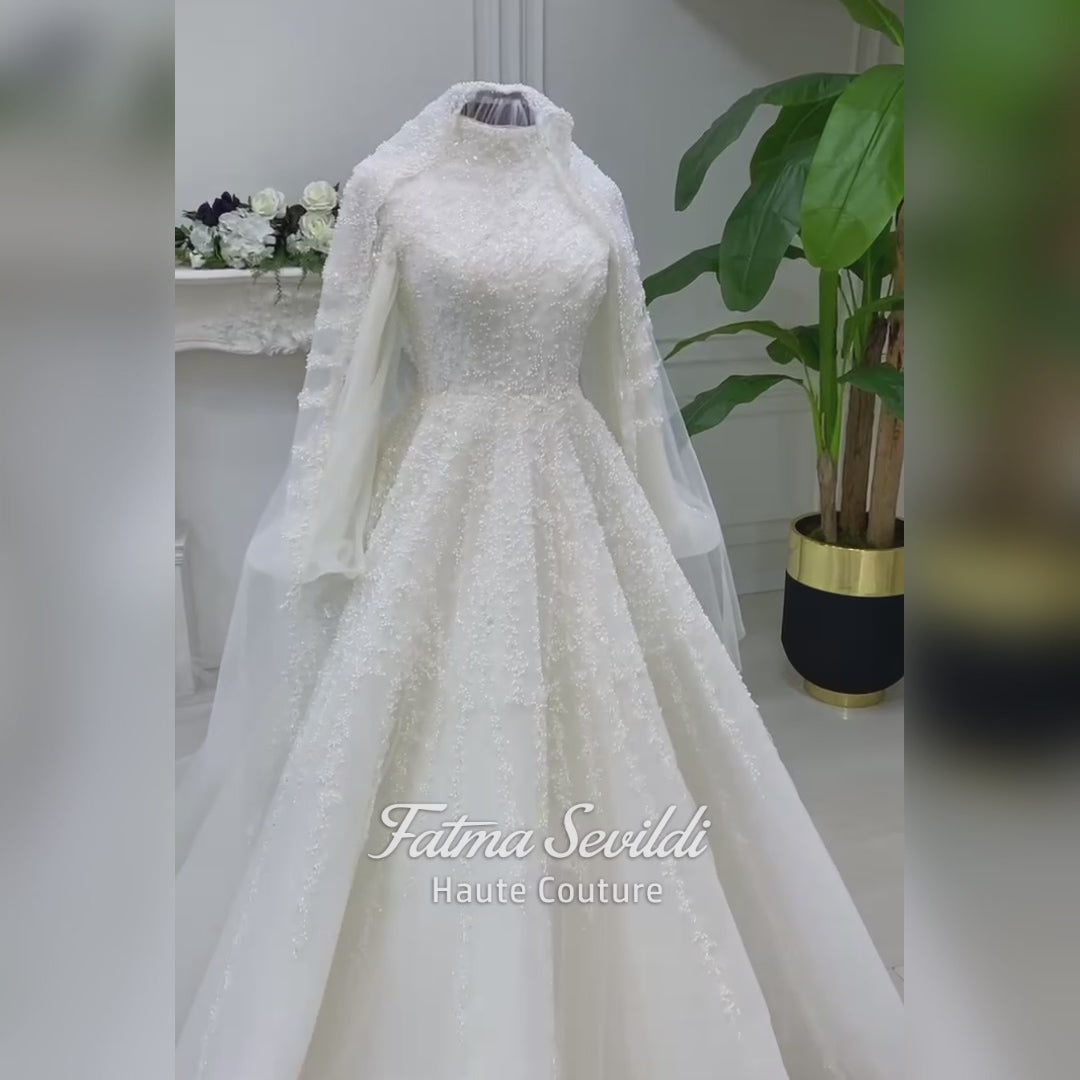 Luxury hijab wedding dress in an A-line tulle ball gown silhouette with long balloon sleeves, high neck, sparkling beadwork, and a lace-edged veil.