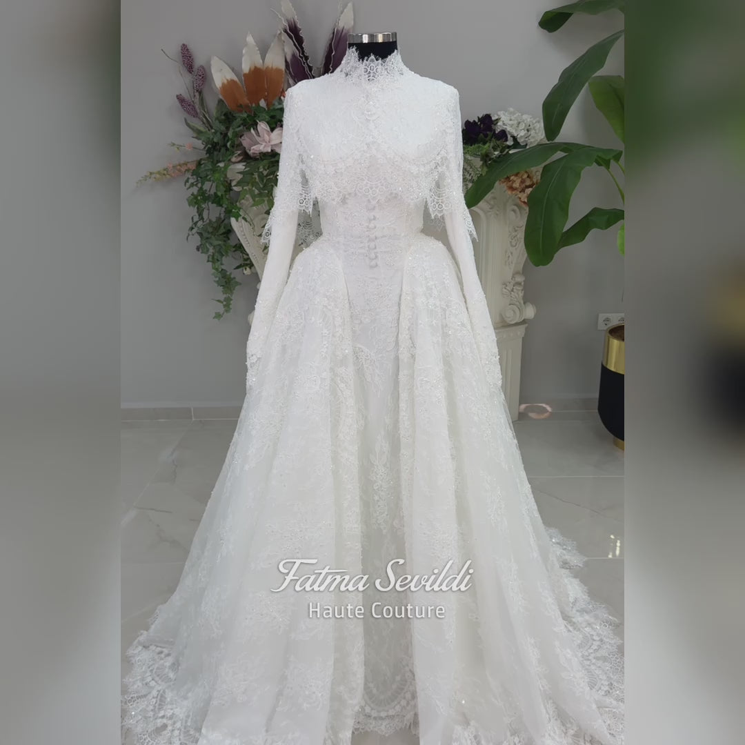 Off-white hijab wedding dress by Fatma Sevildi with beaded floral lace, a basque waist, long sleeves and a high neckline.