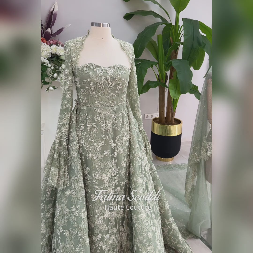 Sage green evening dress with beaded floral lace, a sweetheart neckline and long sleeves with flared lace cuffs, displayed on a mannequin.